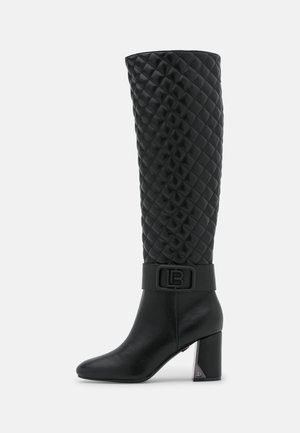 Czarne wysokie kozaki za kolano z pikowanym wierzchem, szerokim paskiem i detalami z logo, blokowany obcas z metalicznym akcentem oraz gładka część palcowa.