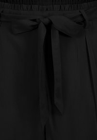 Schwarze Hose mit einem gerafften elastischen Bund und einem gebundenen Stoffgürtel. Glatte Textur mit Falten und ohne sichtbare Muster oder Beschläge.