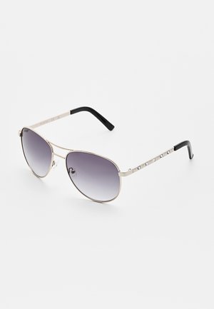 Occhiali da sole aviator in metallo con lenti grigie sfumate, sottile montatura argentata, aste nere e borchie decorative sulle stanghette.