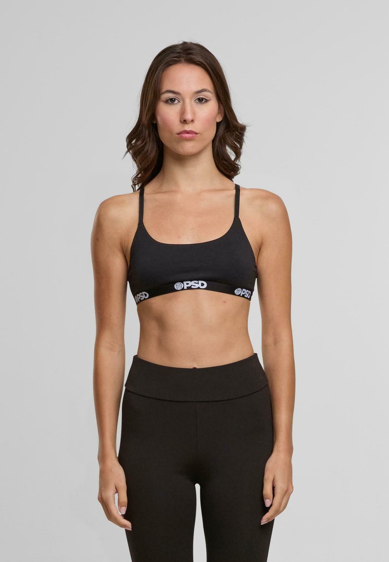 Fekete sportmelltartó vékony pántokkal, fehér nyomtatott logós szalaggal. Az anyag sima és rugalmas, sportolásra tervezve.