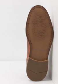 Semelle de chaussure en cuir marron avec texture à motifs, marquée "Mare O'Polo 41", présentant un bord contrastant et une finition lisse.