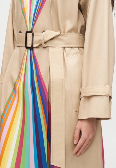 Μπεζ καμπαρντίνα με εσωτερική επένδυση σε ρίγες του ουράνιου τόξου, μέση με ζώνη και μαύρη ορθογώνια αγκράφα, τσέπη με παττίκ και λεπτομέρεια με λουράκι στο μανίκι.