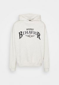 Lichtgrijze hoodie met "WORST BEHAVIOR" in zwart op de borst, voorzien van een voorzak en een capuchon met trekkoord. Zachte textuur.