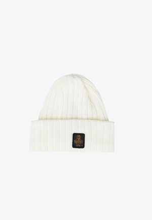 Witte geribbelde gebreide beanie met een omgeslagen rand, voorzien van een zwart rechthoekig label met een logo in goud. Zachte textuur, gezellige uitstraling.