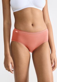 Boxer hipster coral en tissu lisse avec une taille festonnée. Présente une petite étiquette sur le côté pour le branding.