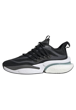 Zapatilla deportiva negra con parte superior de malla, acentos grises y una media suela blanca con una sección translúcida. Equipadas con un diseño de cordones.