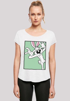 Valkoinen lyhythihainen t-paita, jossa on grafiikka Bugs Bunnysta mintunvihreällä taustalla, mustilla ääriviivoilla ja kirkkaan vaaleanpunaisilla korvakuulokkeilla.