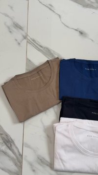 Quattro t-shirt impilati: beige, blu, nero e bianco. Ognuno ha un collo a giro e una texture liscia e morbida. L'etichetta recita "PIER ONE."