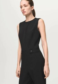 Mono negro sin mangas con un diseño ajustado, textura sutil y bolsillos laterales, que presenta un escote liso y acentos minimalistas.