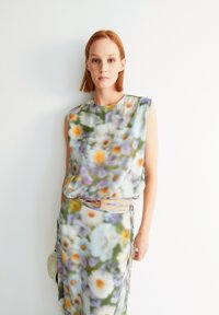 Abito con motivo floreale in tessuto morbido, caratterizzato da una vestibilità rilassata, design senza maniche e una palette di colori pastello con fiori arancioni, viola e bianchi.