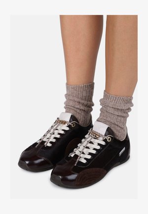 Mørkebrune sneakers med tekstureret materiale, hvide snørebånd og guld hardware detaljer, kombineret med lysebrune ribbede sokker.