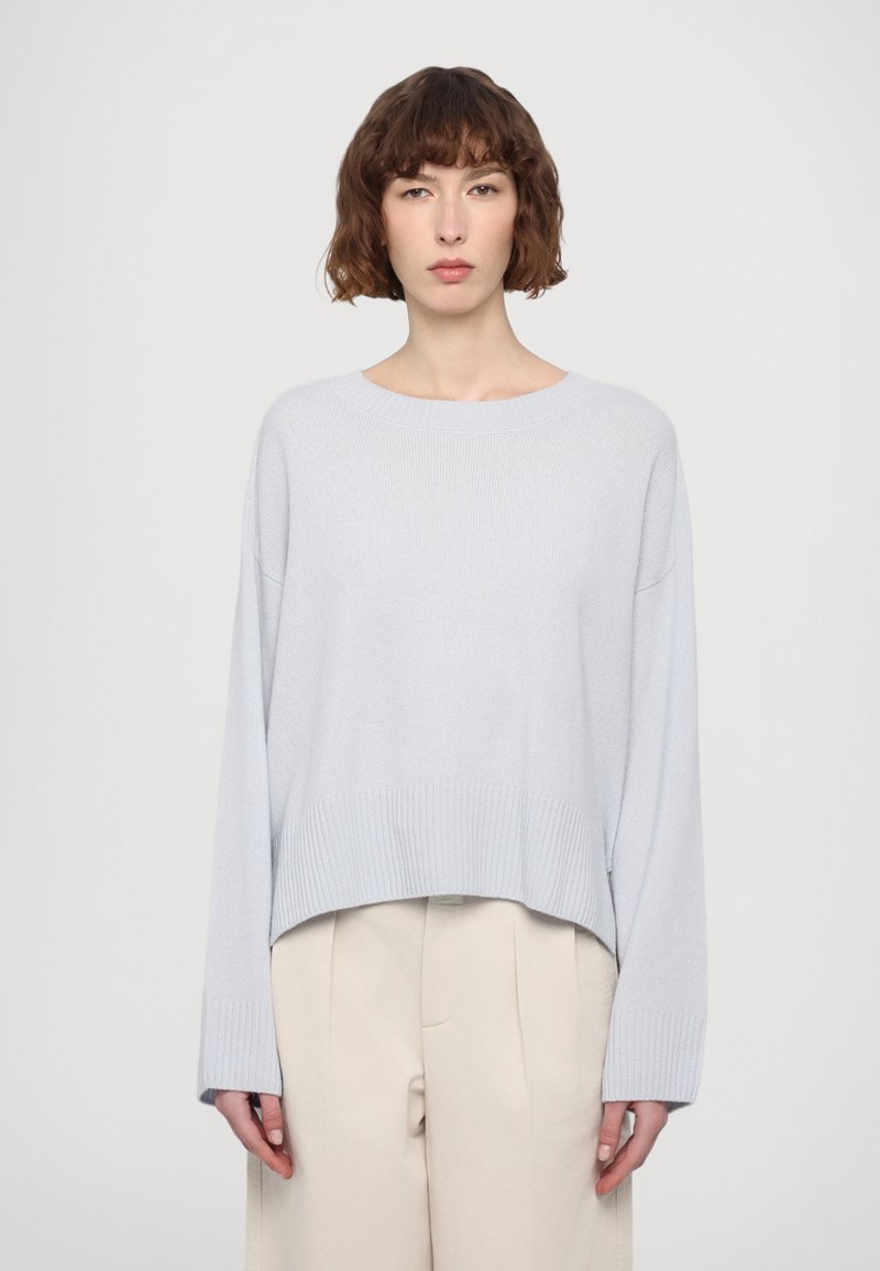 Heled sinine, ribikujuline kootud kook, mis on lõdva istuvusega, laiad varrukad ja lühendatud alläär. Koos kreemja värvi laia säärega pükstega.