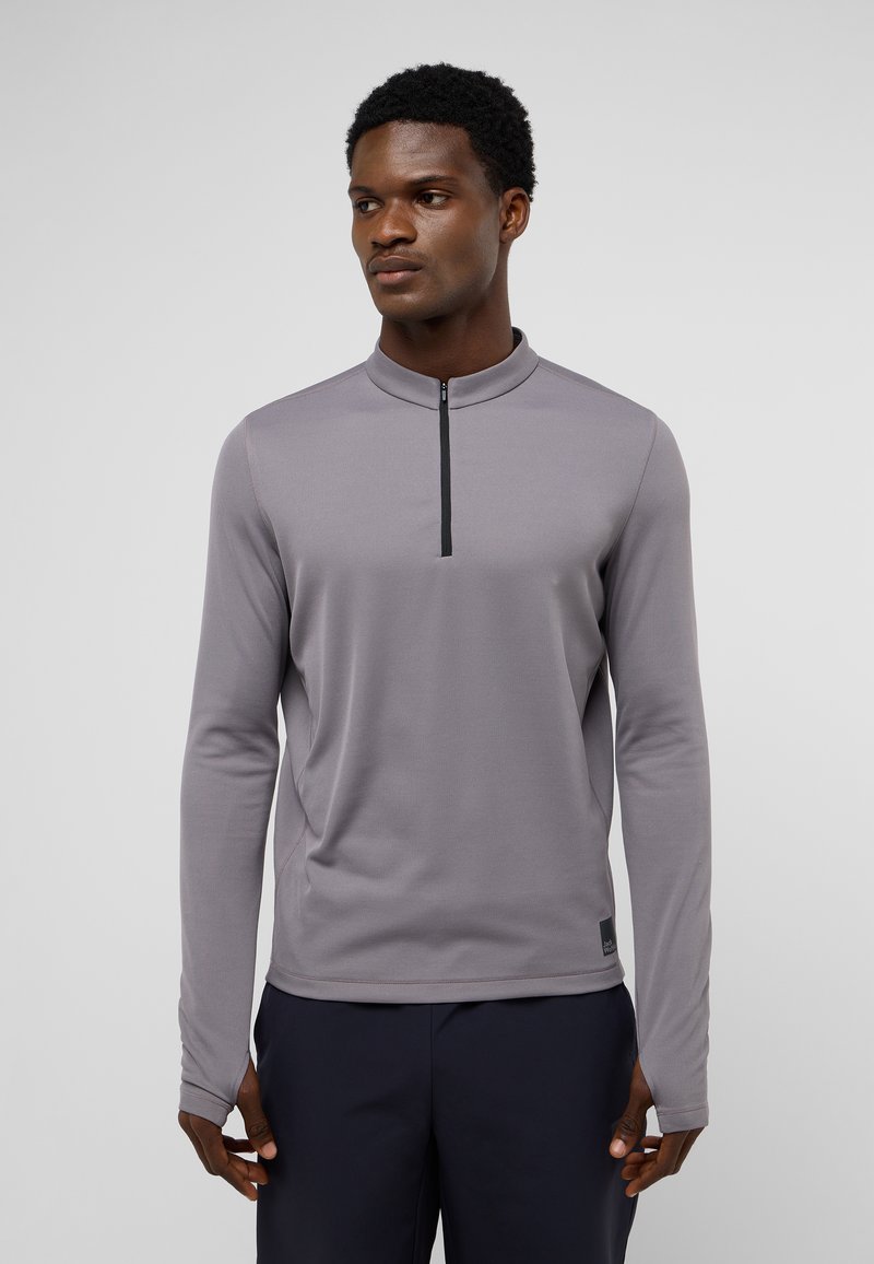 Pullover a maniche lunghe di colore grigio chiaro con zip a un quarto e colletto rialzato. Presenta un design aderente e un tessuto liscio e strutturato.