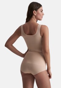 Beige naadloze tanktop met brede banden, gecombineerd met bijpassende hoge shorts. Glad textuur en minimalistisch ontwerp. Achteraanzicht weergegeven.