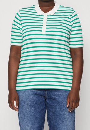 Polo à rayures vertes et blanches avec col, manches courtes et trois boutons ; porté avec un jean en denim bleu.