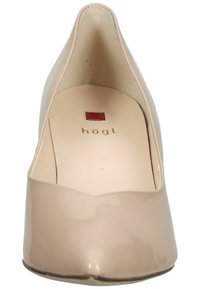 Beżowe lakierowane szpilki z wąskim noskiem, gładką teksturą i subtelnym oznakowaniem wewnętrznym w złotym i czerwonym. Zapięcie z tyłu.