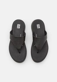 Sandali flip-flop neri con una larga fascia superiore e un inserto per le dita, realizzati in materiale simile alla pelle, con una soletta texturizzata e suola piatta.