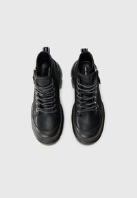 Zwarte leren hoge sneakers met grijze veters, zijrits, afgeronde neus, gestructureerde zool en een logotab op de hiel.