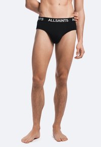 Black brief underwear with a soft fabric, elastic waistband featuring "ALLSAINTS" logo in white, showcasing a snug fit and smooth texture.