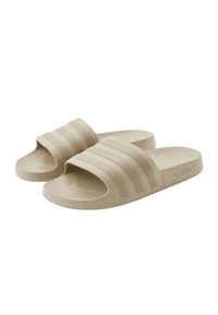 Infradito beige con tre strisce rialzate sulla banda superiore. Realizzati con materiale morbido, con una soletta testurizzata e dettaglio del logo sul lato.