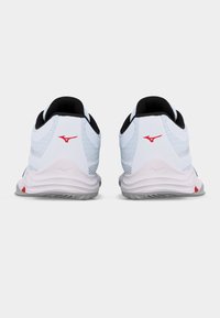 Ζευγάρι από λευκά και γκρι αθλητικά παπούτσια με μαύρα εσωτερικά και κόκκινα λογότυπα, από πίσω σε λευκό φόντο.