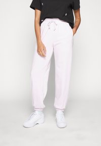 Ljusrosa joggers med resårmidja och muddar, med sidofickor. Matchas med vita sneakers och en svart t-shirt med kort ärm.