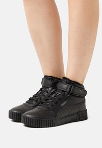 Baskets montantes noires avec une finition en cuir texturé, dotées d'une sangle et de lacets, d'une semelle striée et d'accents en fausse fourrure autour du col.