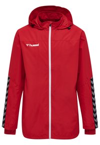 Röd lättviktsjacka med huva, vit dragkedja, svarta chevron-mönstrade detaljer på ärmarna och "hummel"-logotyp på bröstet.