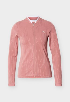 Veste zippée à manches longues, rose poudré, avec un motif ondulé subtil et un petit logo blanc sur le haut à gauche de la poitrine.