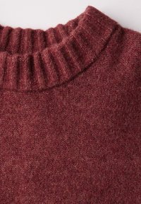 Pull en tricot bordeaux avec un col côtelé. La texture semble douce, présentant un motif chiné subtil sur l'ensemble du tissu.