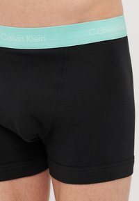 Schwarze Boxershorts mit einem hellblauen Calvin Klein Logo-Bund. Hergestellt aus glattem Stoff, mit einer taillierten Passform und flachen Nähten.