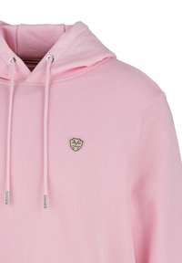 Rosa Baumwollkapuzenpullover mit einer Vorderreißverschlusstasche, verstellbaren Kordeln und einem kleinen goldenen Emblem, das das Jahr "1969" und "Italia" zeigt.