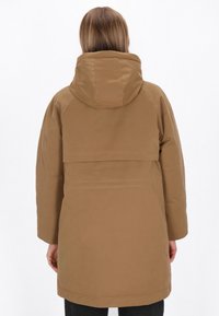 Bruine capuchonparka met een ontspannen pasvorm, voorzien van een achterste schouderpas en stikdetails. Het materiaal heeft een soepele, gestructureerde afwerking.