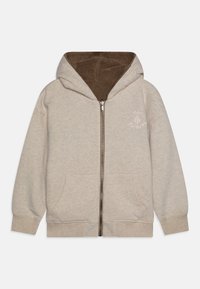 Felpa con zip beige con fodera in pile marrone, tasche frontali e logo ricamato sul petto. Presenta polsini e orlo a coste.