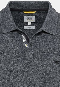 Mørkegrå organisk polo skjorte med tekstileret stof, to-knaps placket og kontrasterende sort krave. Har logo på venstre side.