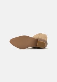 Beige Stiefelette mit einer glatten Oberfläche, runder Zehenpartie und mittelhohem Blockabsatz. Flexible Gummisohle mit strukturiertem Muster für besseren Grip.