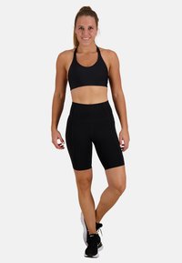 Svart sport-bh med texturerad design, kombinerad med hög midja svarta cykelshorts. Båda är figurnära och tillverkade av elastiskt material.