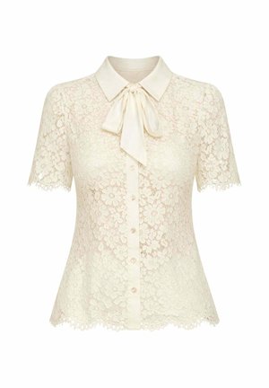 Blusa corta in pizzo crema con maniche corte, motivo floreale, chiusura frontale con bottoni, scollo con colletto e fiocco in raso annodato al collo.