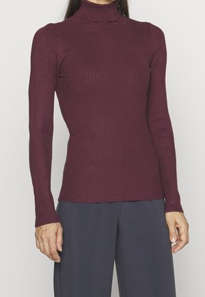 Bordeauxfarbener gerippter Rollkragenpullover mit langen Ärmeln, taillierter Passform und kontrastierender Textur zu dunklen Hosen. Aus glattem Strickstoff.
