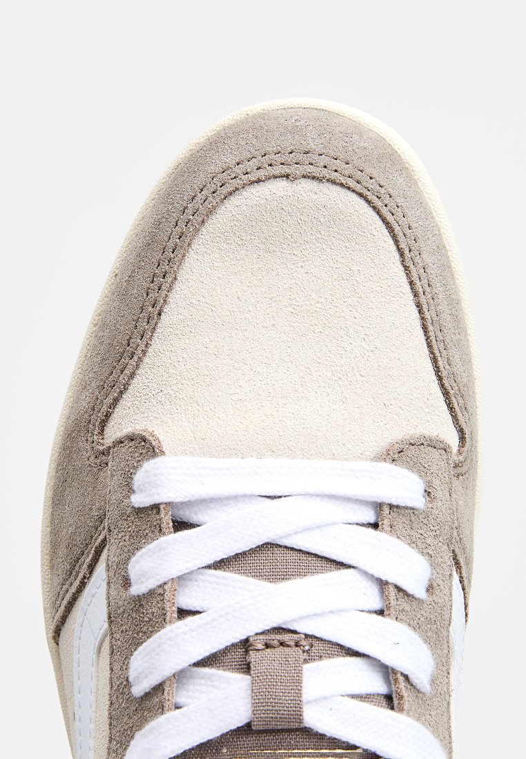 Beige und cremfarbene Wildledersneaker mit weißen Schnürsenkeln, genähten Akzenten und einem glatten Zehenkappen-Design. Texturiertes Obermaterial und Logo-Detail.