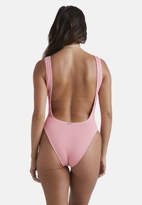 Costume da bagno intero rosa a costine con spalline larghe, design a schiena bassa e gambe alte che mettono in risalto il punto vita.