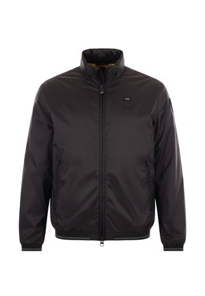 Giacca nera con zip e colletto alla coreana, tasche laterali con zip e piccola toppa nera sul petto sinistro e sulla manica.