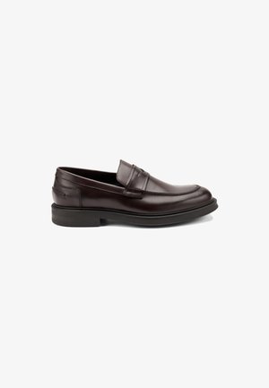Mocasines de cuero marrón con una textura suave, que presentan un diseño cosido en la punta y una suela baja de goma para mayor comodidad.