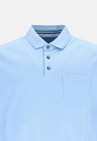 Lysblå polo t-shirt med tre mørke knapper, en lomme på venstre bryst og en kontrasterende stribet krave. Glat bomuldsstof.