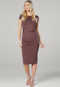 Mauve-farbenes, tailliertes Midikleid mit kurzenÄrmeln, gerafften Seitendetails und weichem Stoff. Getragen mit silbernen Ankle-Strap-Absätzen. Einfaches, elegantes Design.