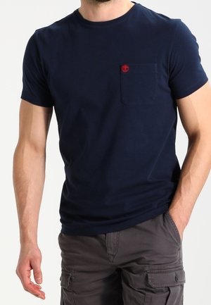 Navy blue short-sleeve T-shirt made of cotton. Features a front pocket with a red logo detail. Smooth texture and standard fit.