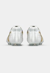 Beli nogometni kopački z zlatimi kovinskimi poudarki, gladkim teksturiranim zaključkom in nizkim dizajnom. Imajo zaobljen prst in oblikovane žeblje.