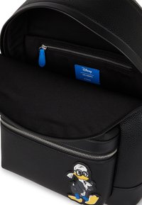 Melns mugursomā ar strukturētu virsmu, kurai ir izcelta Donald Duck uzlīme. Iekšpusē ir zilā birka un kabata ar rāvējslēdzēju.