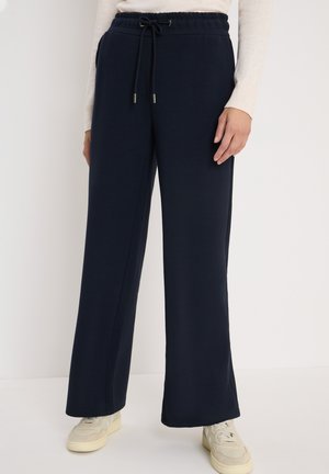 Pantaloni a gamba larga blu navy realizzati in tessuto morbido, con vita elastica e cordoncino, dotati di tasche laterali e una texture liscia.