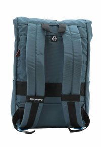 Mochila color azul verdoso con correas acolchadas y un asa superior. Presenta un logo negro, está hecha de material reciclado y tiene una forma rectangular.